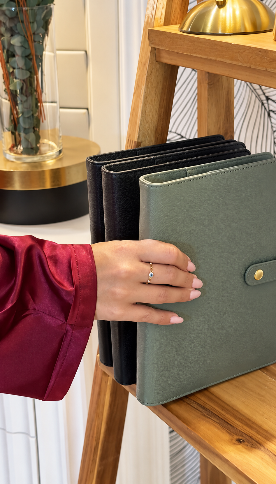 A hand pulling the sage Thryve journal off a wooden shelf